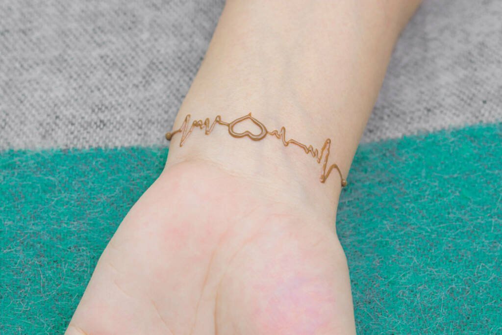 Heartbeat henna tattoo on a person s wrist